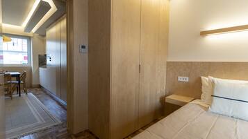 Un dormitorio con cama, armario de madera y una mesita de noche.