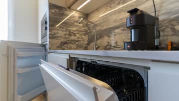 Eine Küche mit eingebautem Geschirrspüler, einer Kaffeemaschine auf der Arbeitsfläche und einer Marmor-Spritzschutzwand.