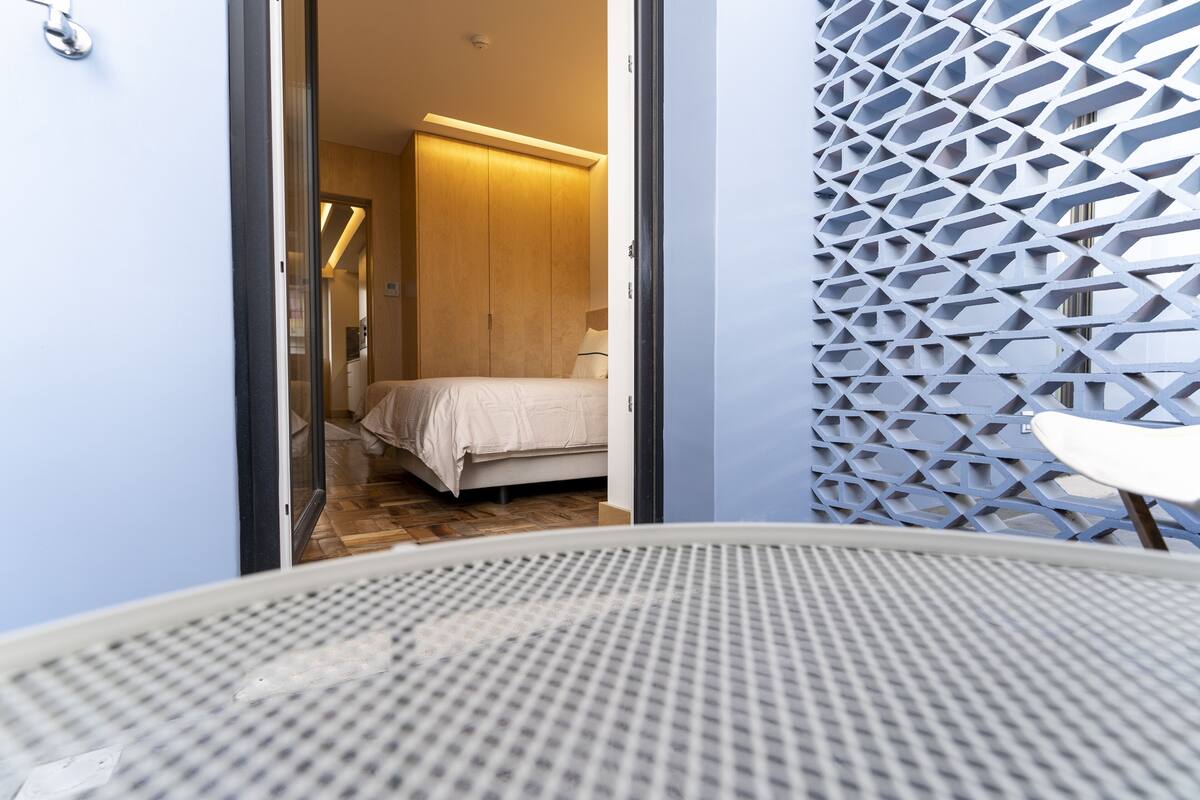 Een hotelkamer met een bed, een kleintje tafeltje en een decoratief wandpaneel.
