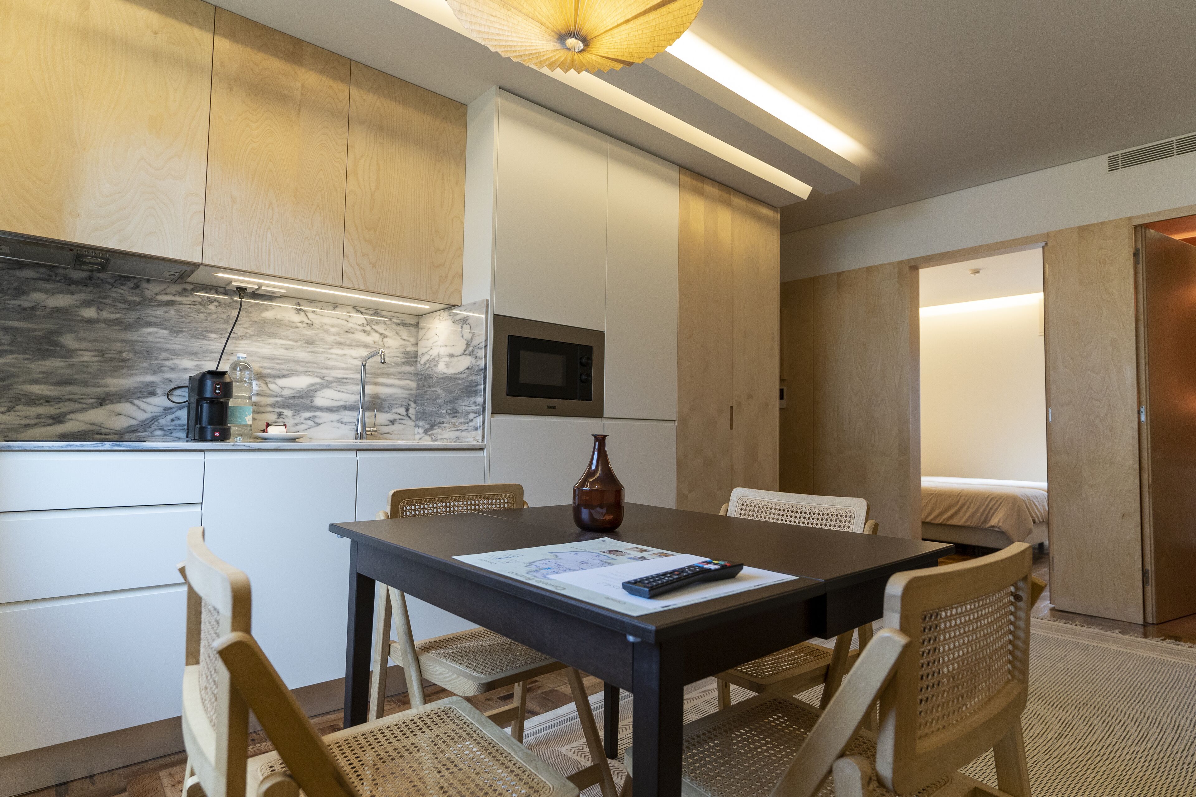 Una cocina moderna con salpicadero de mármol, armarios de madera y un comedor con mesa y sillas.