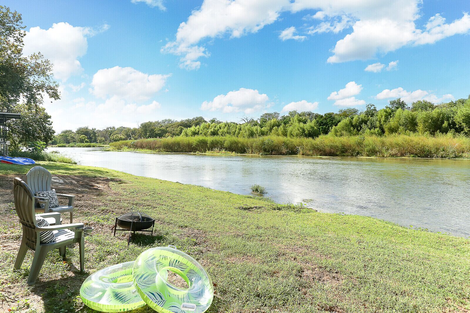 A riverside setting with a chair and inflatable rings on the grass.