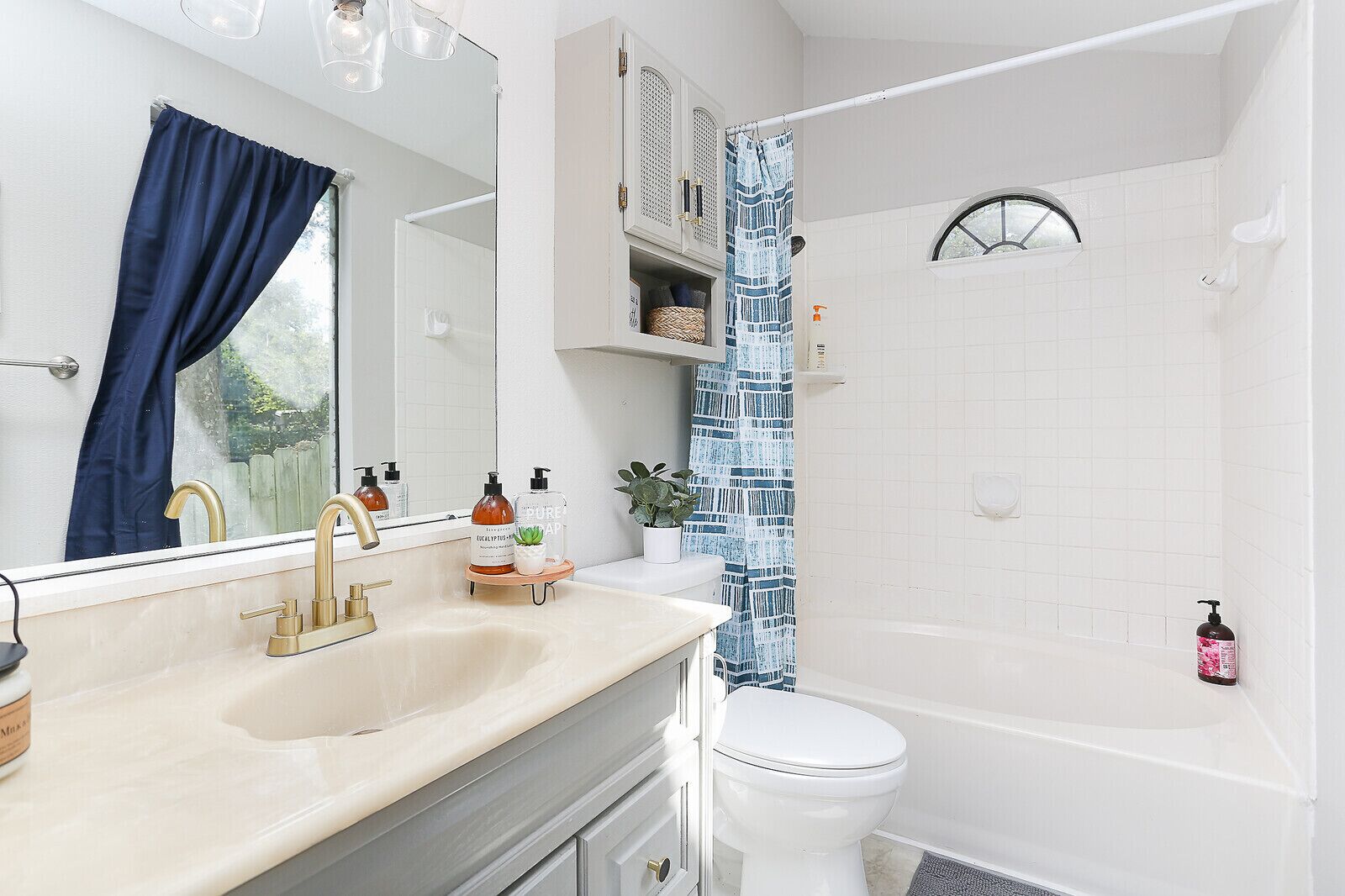 A bathroom with a sink, mirror, toilet, and bathtub.