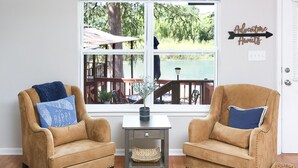 Una habitación con dos sillones de cuero, una mesita con una cesta tejida y vistas a una terraza y zona exterior a través de un ventanal grande.