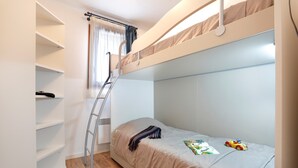 Una litera con una escalera, una estantería y un coche de juguete en la cama.