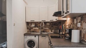 A compact kitchen with a washing machine, a sink, and a stone backsplash. - Holiday apartment with sea view, air conditioning and close to the beach (Klimno)