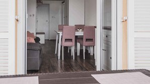 An open doorway leading to a room with a dining table and chairs, a small kitchenette, and a door to another room. - Holiday apartment with sea view, air conditioning and close to the beach (Klimno)