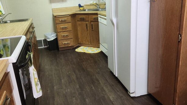 Cocina con armarios de madera, un refrigerador blanco y un microondas.