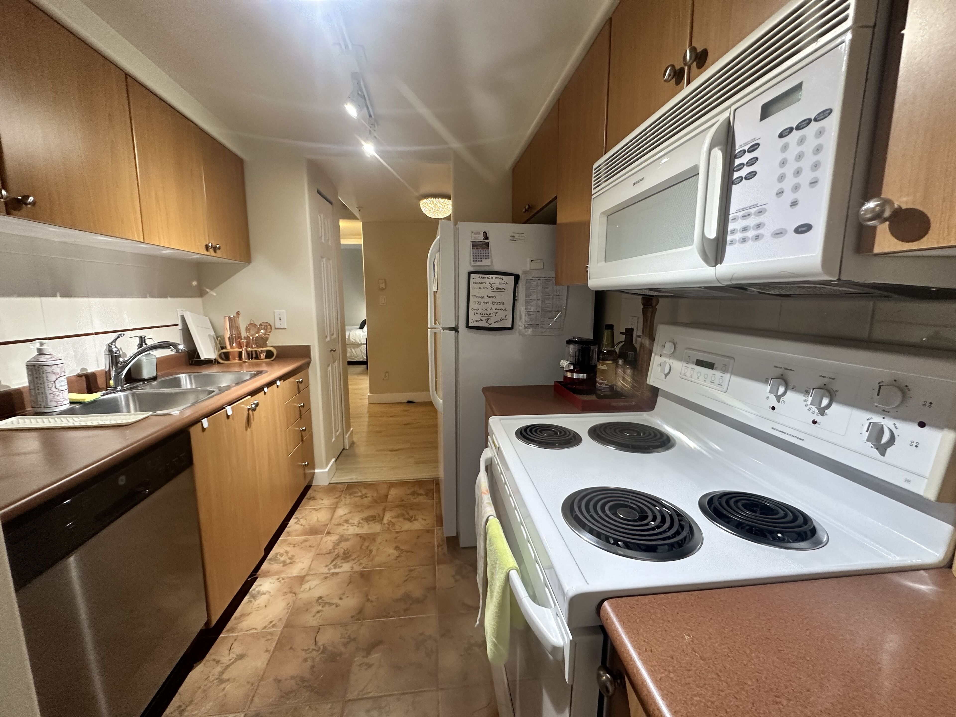 A kitchen with wooden cabinets, a white stove, a microwave, and a refrigerator.