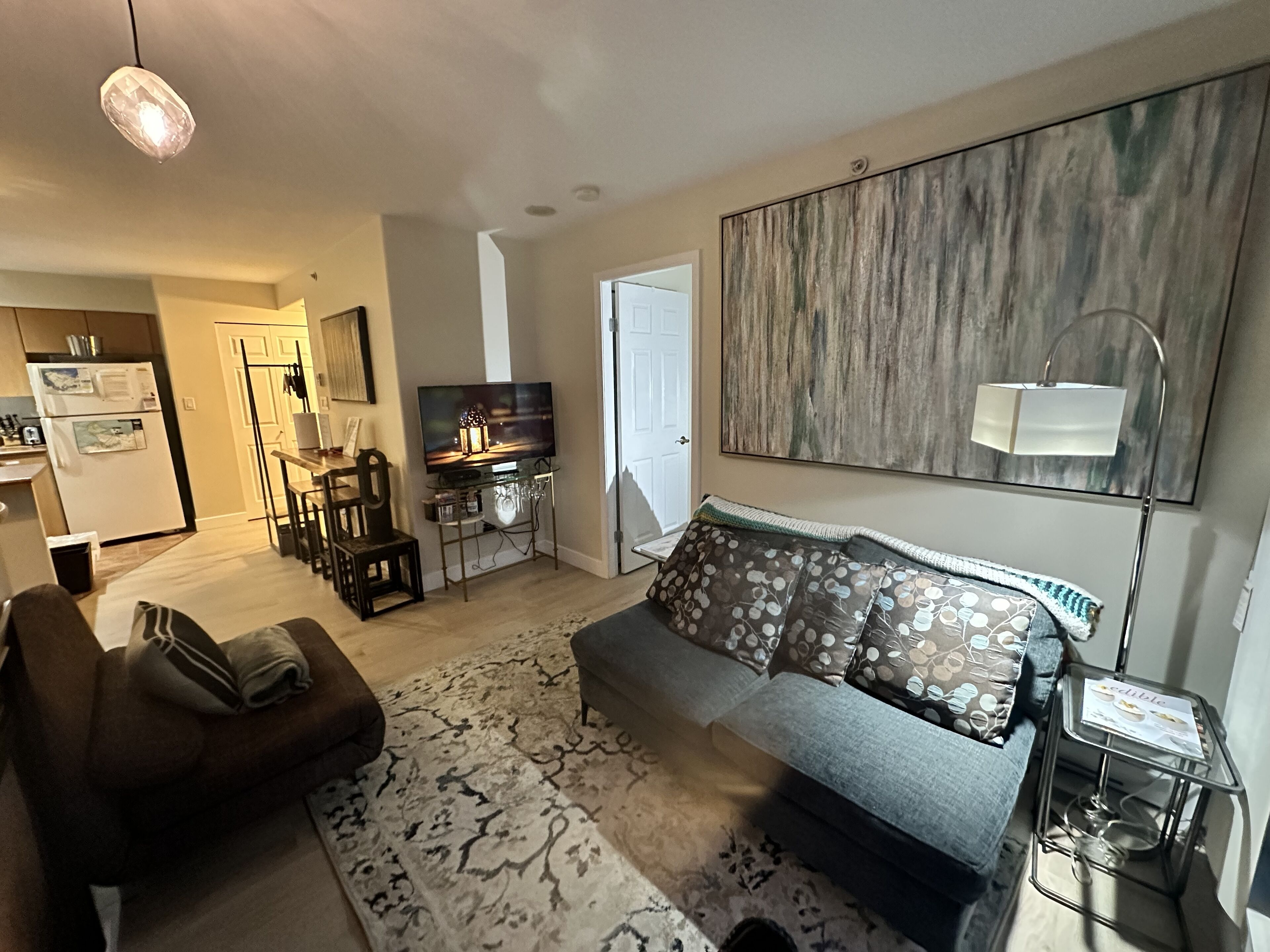 A modern living room with a sofa, a coffee table, a TV, and a dining area with chairs and a table.