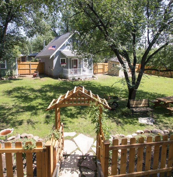 Una propiedad residencial con un patio cubierto, cerca de madera y césped.