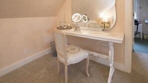 Une coiffeuse blanche avec un grand miroir, deux lampes rondes et un petit plateau contenant des articles de toilette.