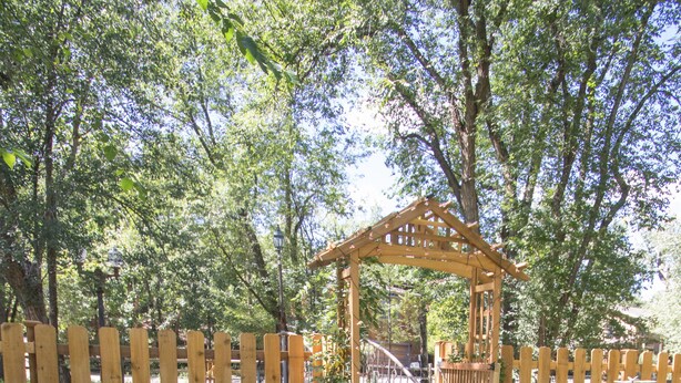 Un jardin agrémenté d’une pergola en bois, d’une borne d’incendie et de diverses fleurs.