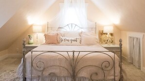 Une chambre mansardée chaleureuse, avec un lit, un lustre et un couvre-lit à baldaquin.