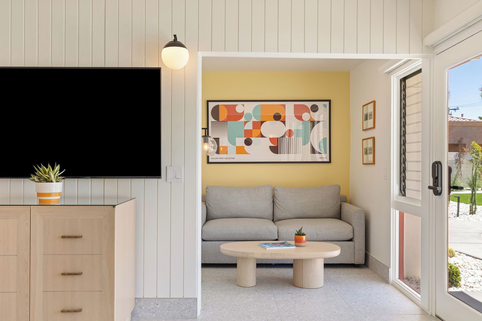 Un salon moderne avec un téléviseur à écran plat, un canapé, une table basse et une plante en pot.