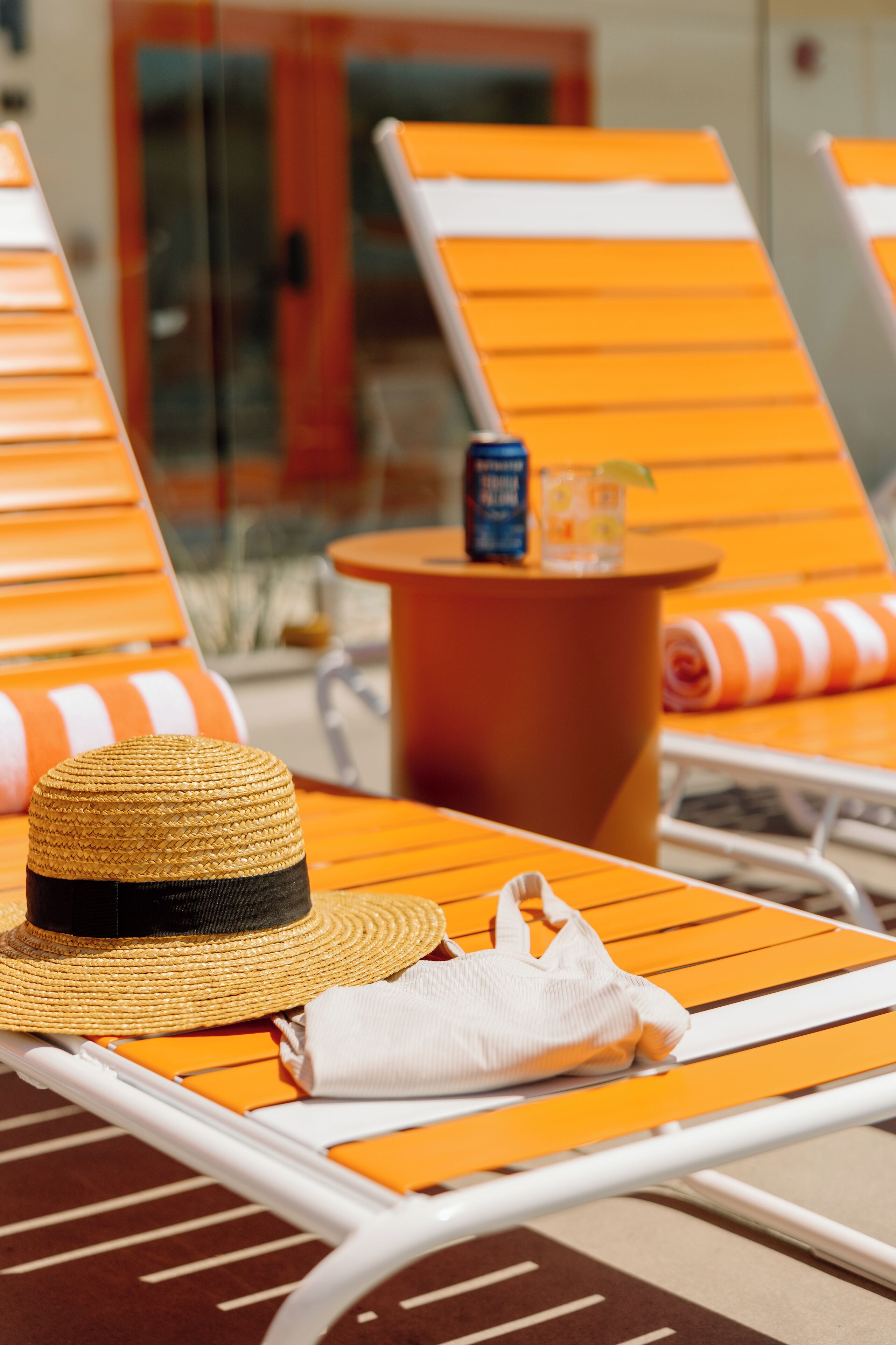 A sun loung Chair with a straw hat and a white towel.