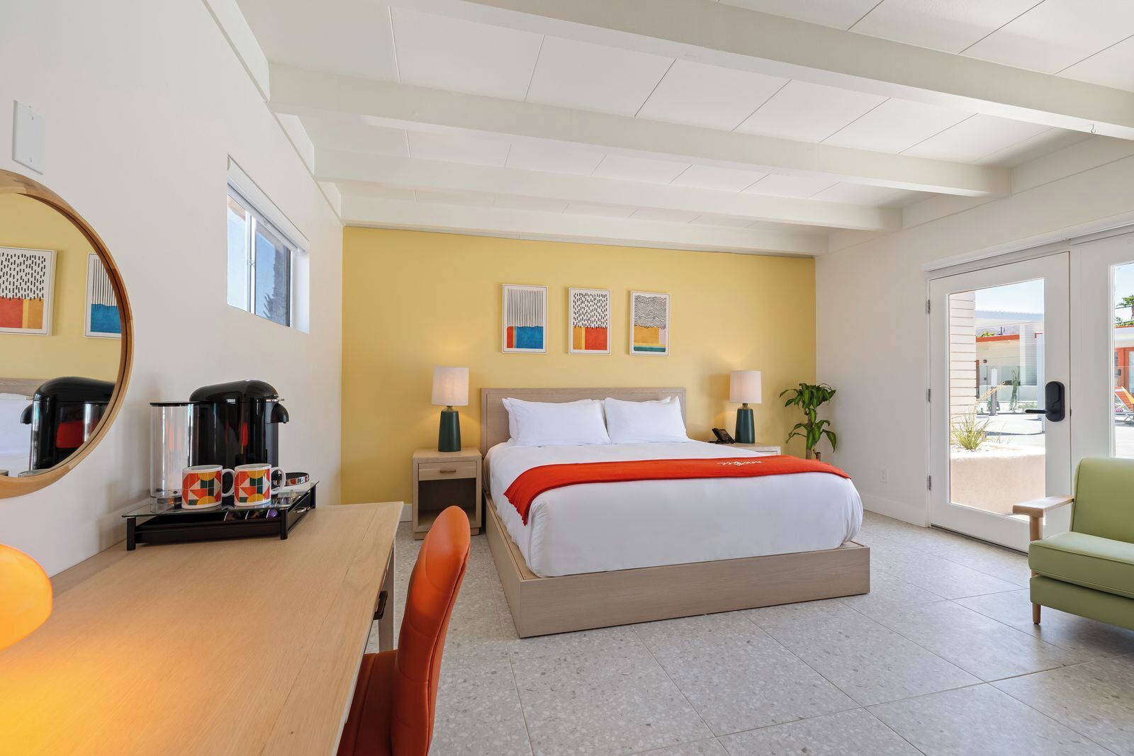 Quarto de hotel com cama, mesas de cabeceira, escrivaninha, poltrona, espaço para café e vista para o exterior.