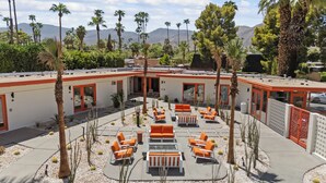 A courtyard with outdoor seating, palm trees, and a view of mountains. - Mojave Resort - Adults Only (Palm Desert)
