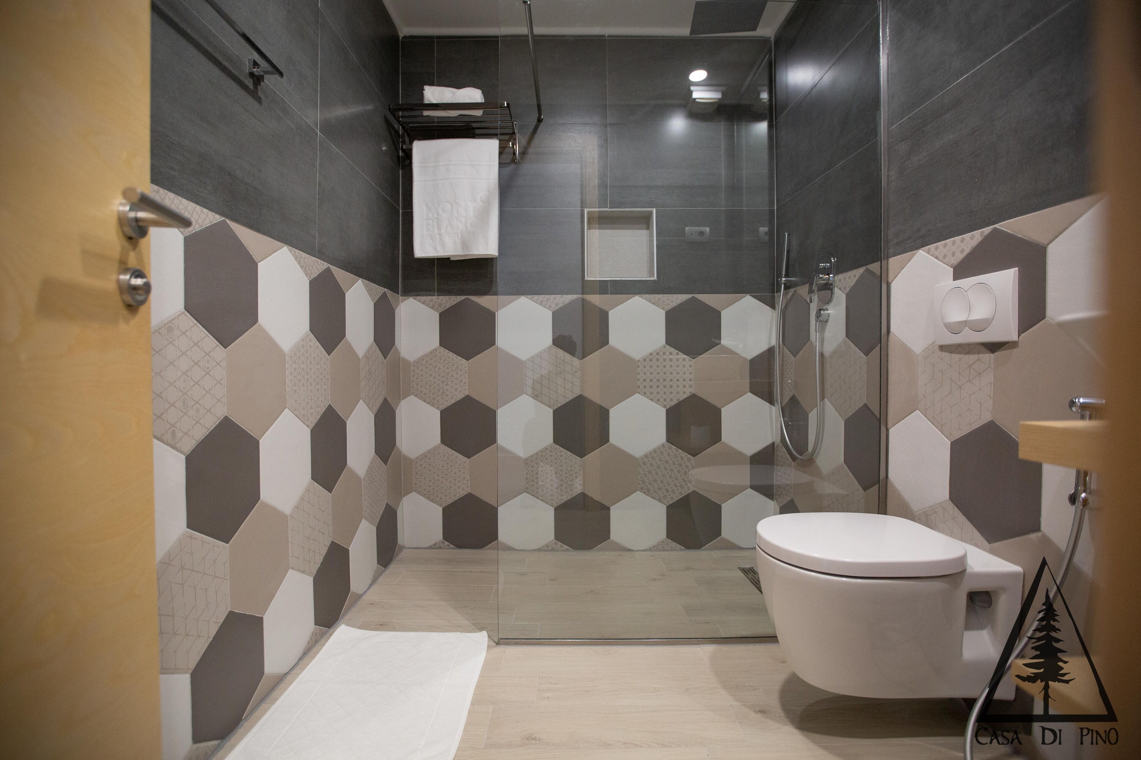 Une salle de bain moderne avec une douche à parois de verre, des toilettes blanches et un porte-serviettes.