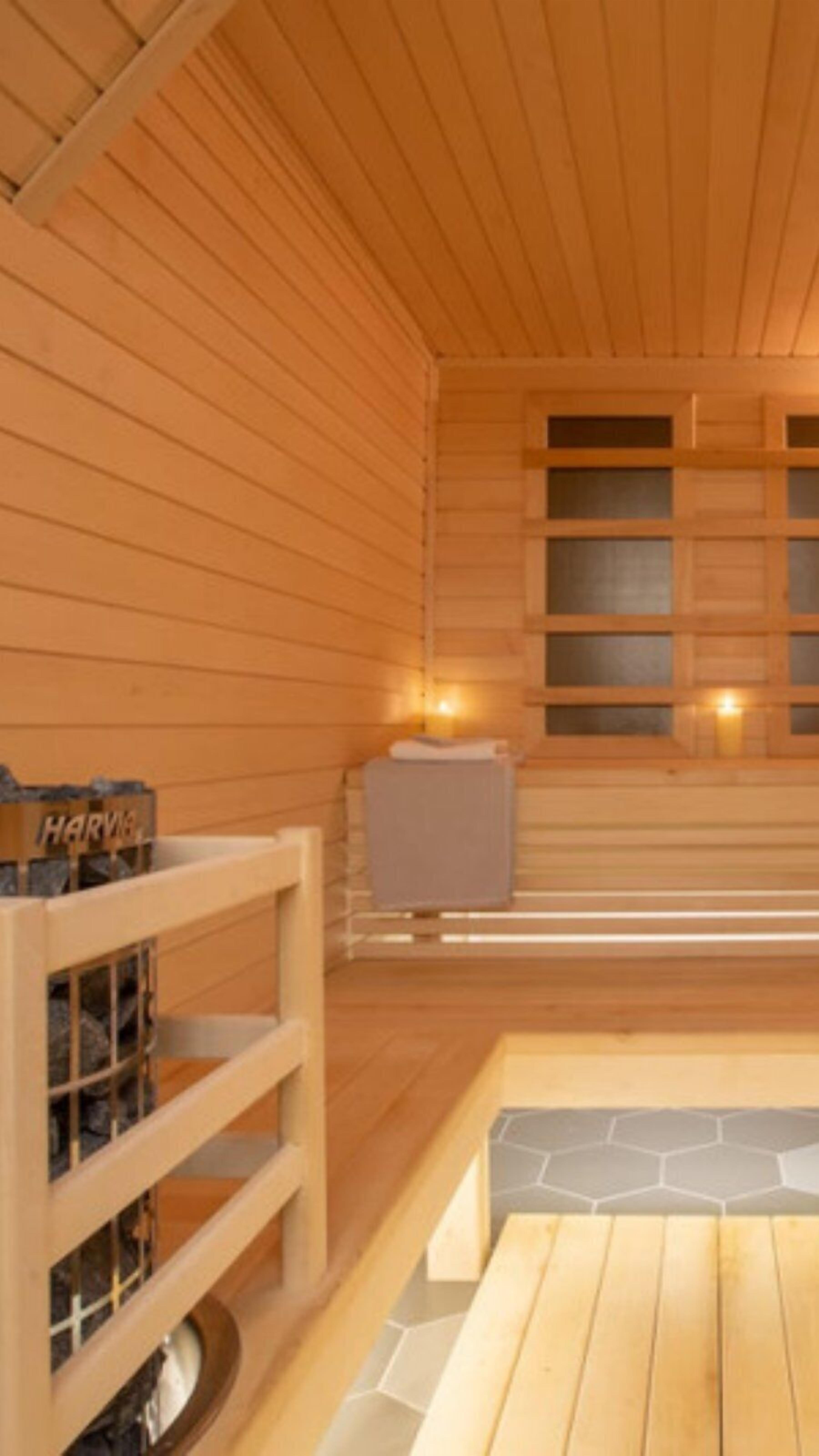 Un sauna en bois, avec un banc, un appareil de chauffage et une fenêtre.