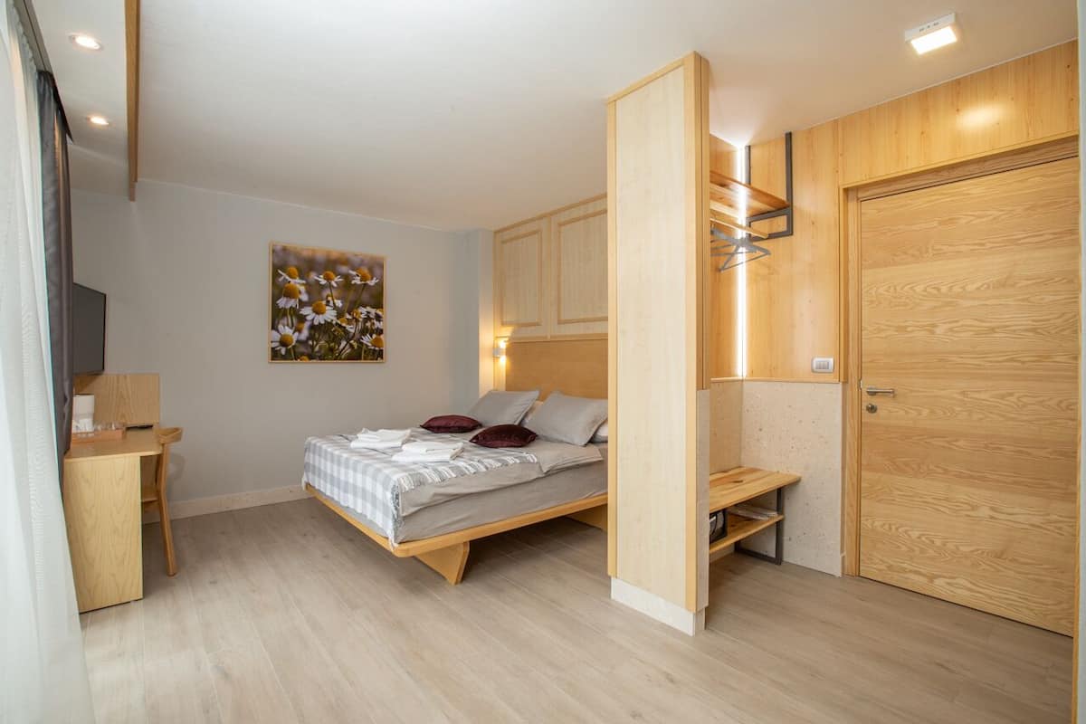Une chambre à coucher avec un lit, un bureau, une armoire et un tableau au mur.