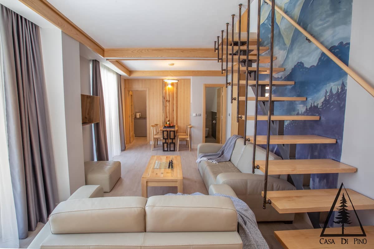Un salon moderne avec un canapé, une table basse et un tableau représentant un paysage de montagne.
