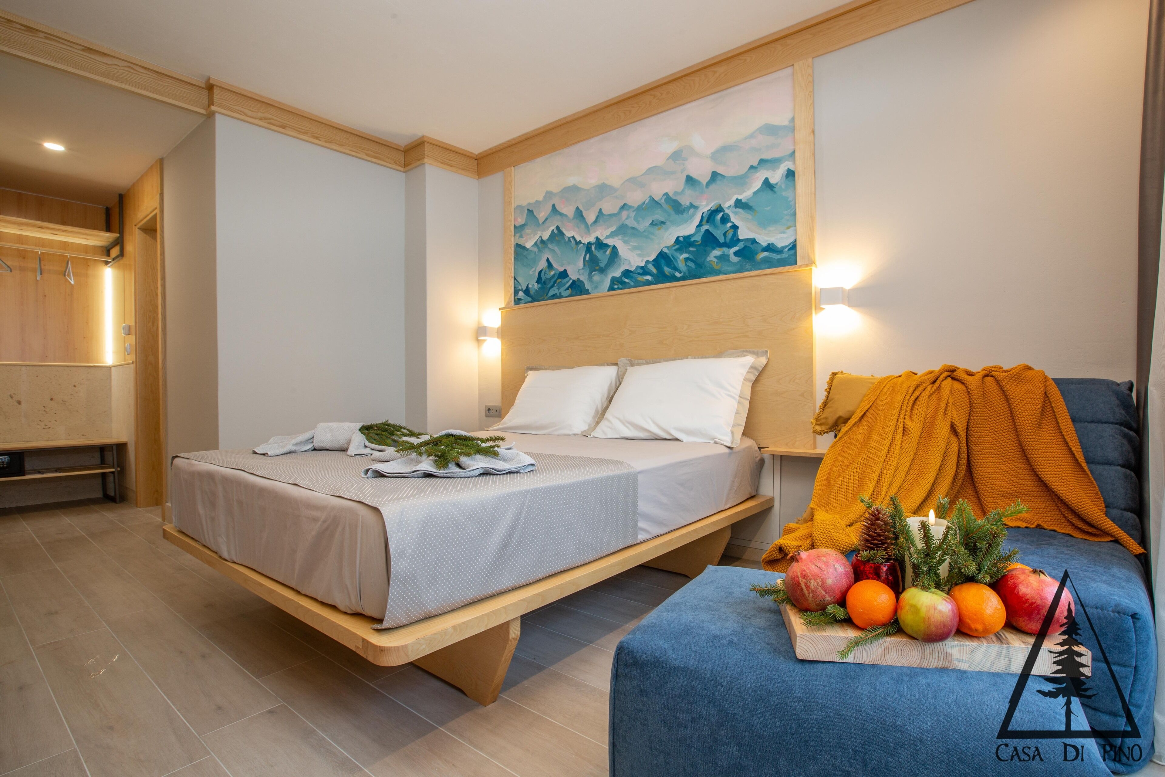 Una camera da letto moderna con un letto, un comodino con della frutta, un quadro appeso e una panca di legno.