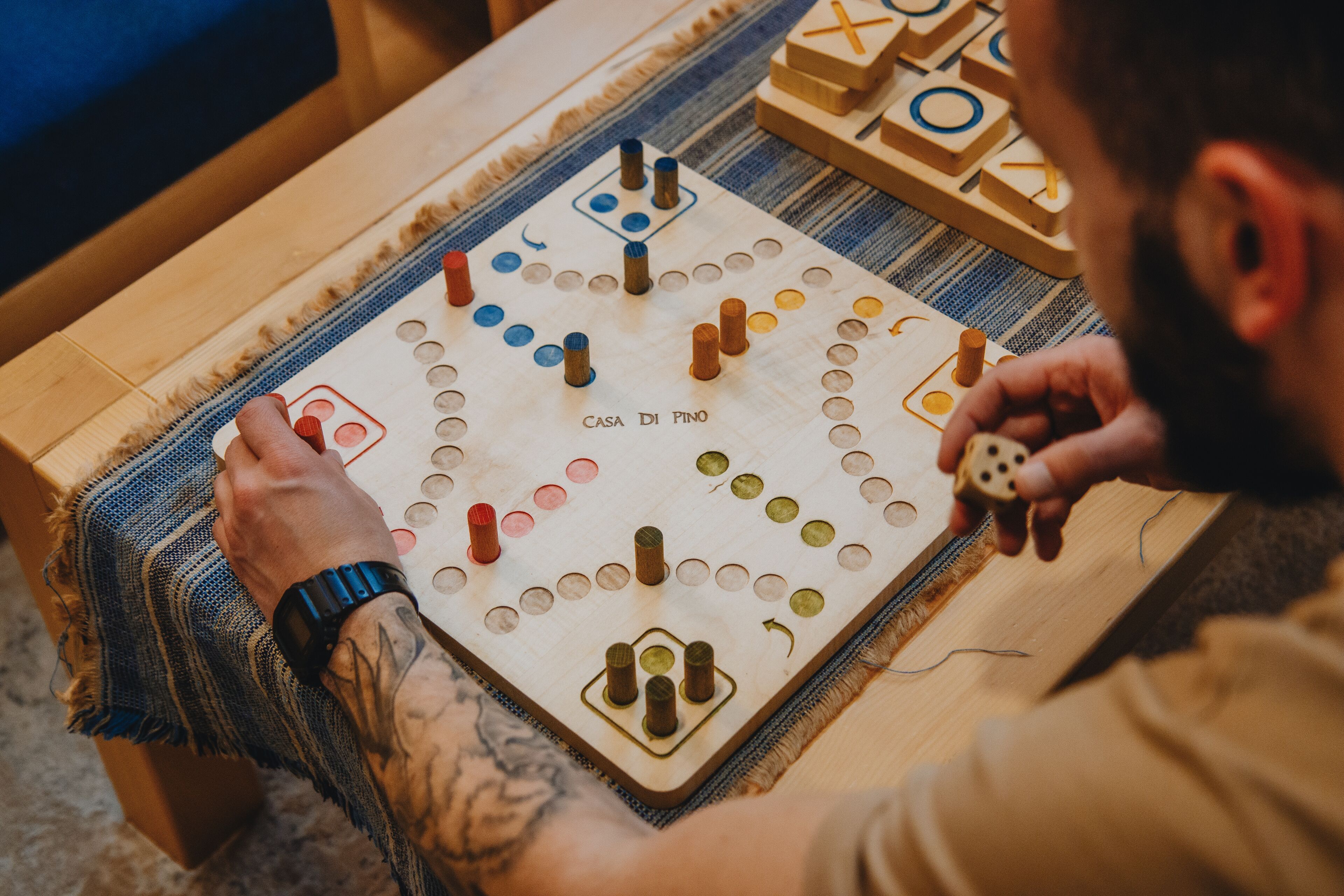 Een houten bordspel met een rasterpatroon en diverse gekleurde stukken, wat een strategisch spel aangeeft.