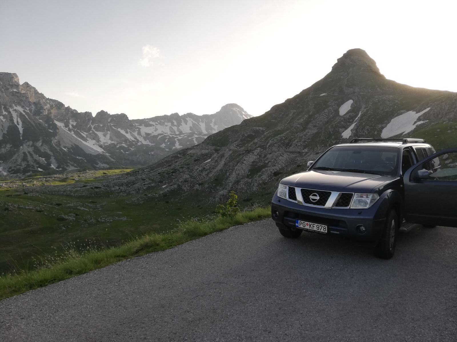 A Nissan SUV parked on a road with a mountainous landscape in the background.