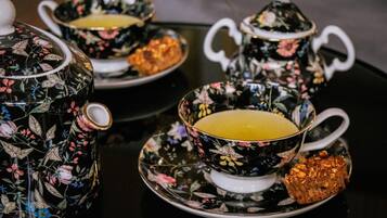 Un service à thé orné de motifs floraux, posé sur une table noire et blanche.