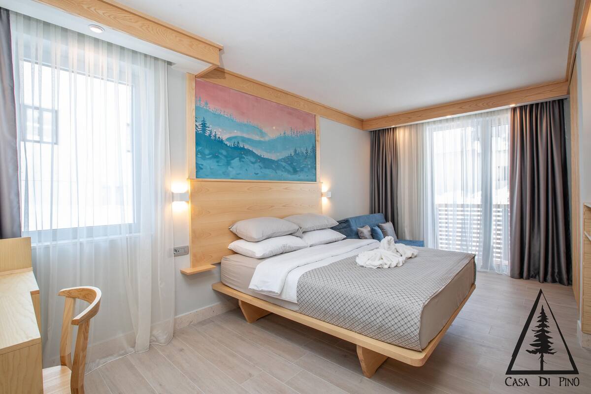 Une chambre à coucher avec un lit, une chaise, un tableau et un logo sur le sol.