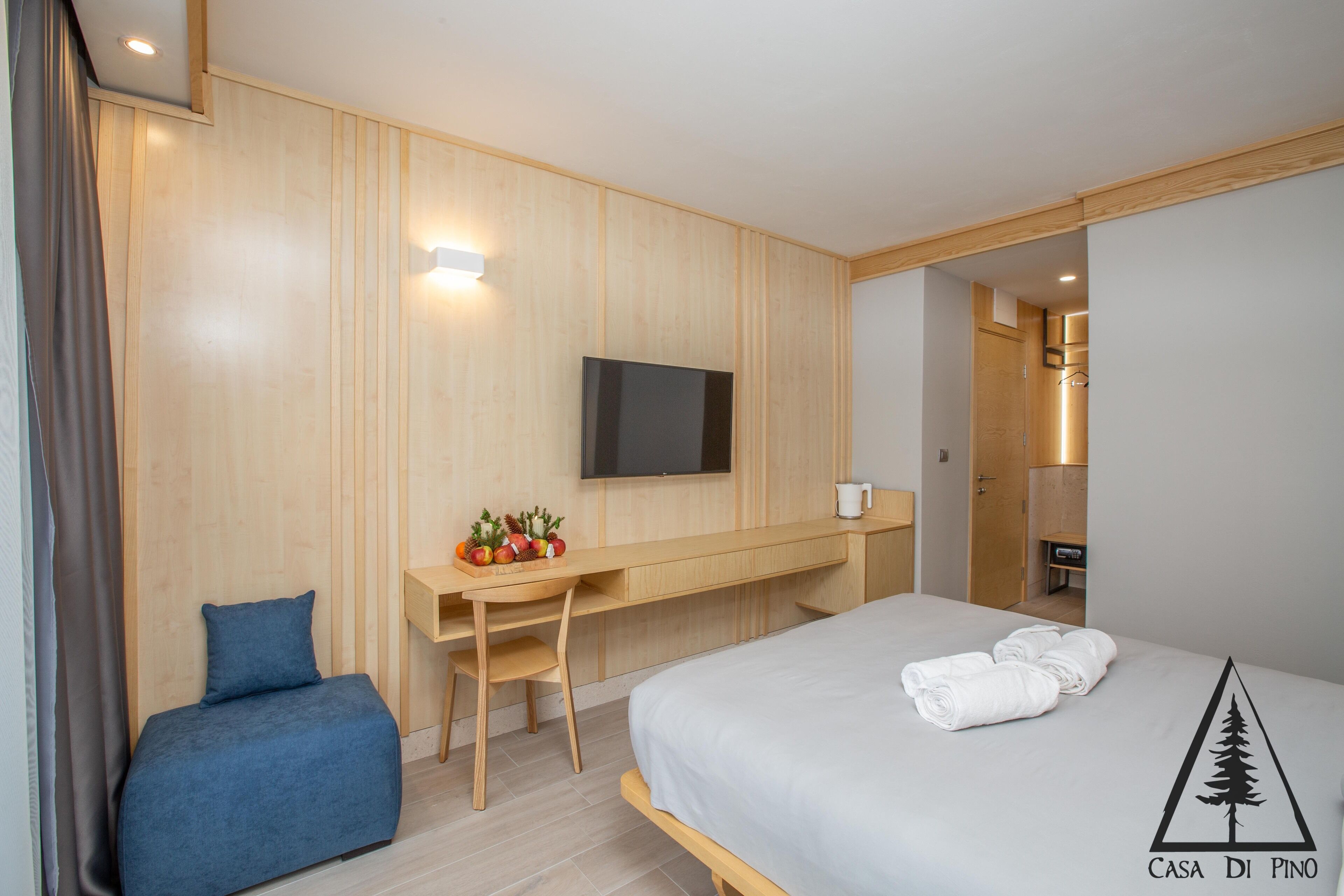 Une chambre d’hôtel moderne équipée d’un lit, d’un bureau, d’une télévision et d’un petit coin salon.