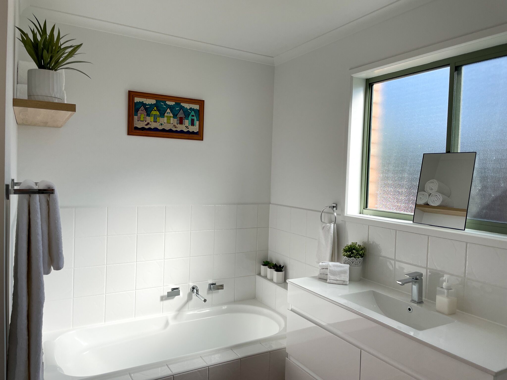 Ein modernes Badezimmer mit Badewanne, Waschbecken und einem Fenster mit Aussicht.
