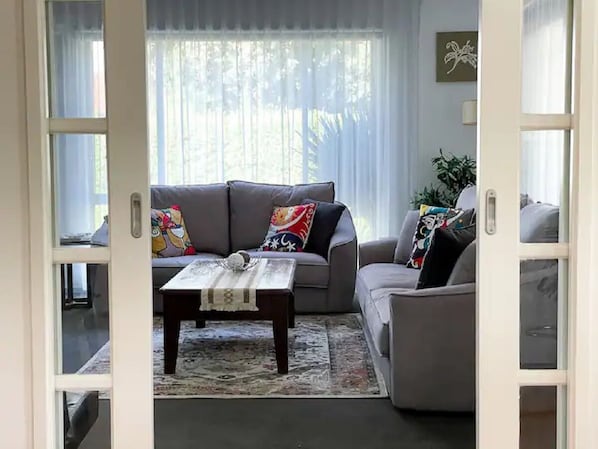 Ein Wohnzimmer mit grauem Sofa, einem Couchtisch und einem gemusterten Teppich.