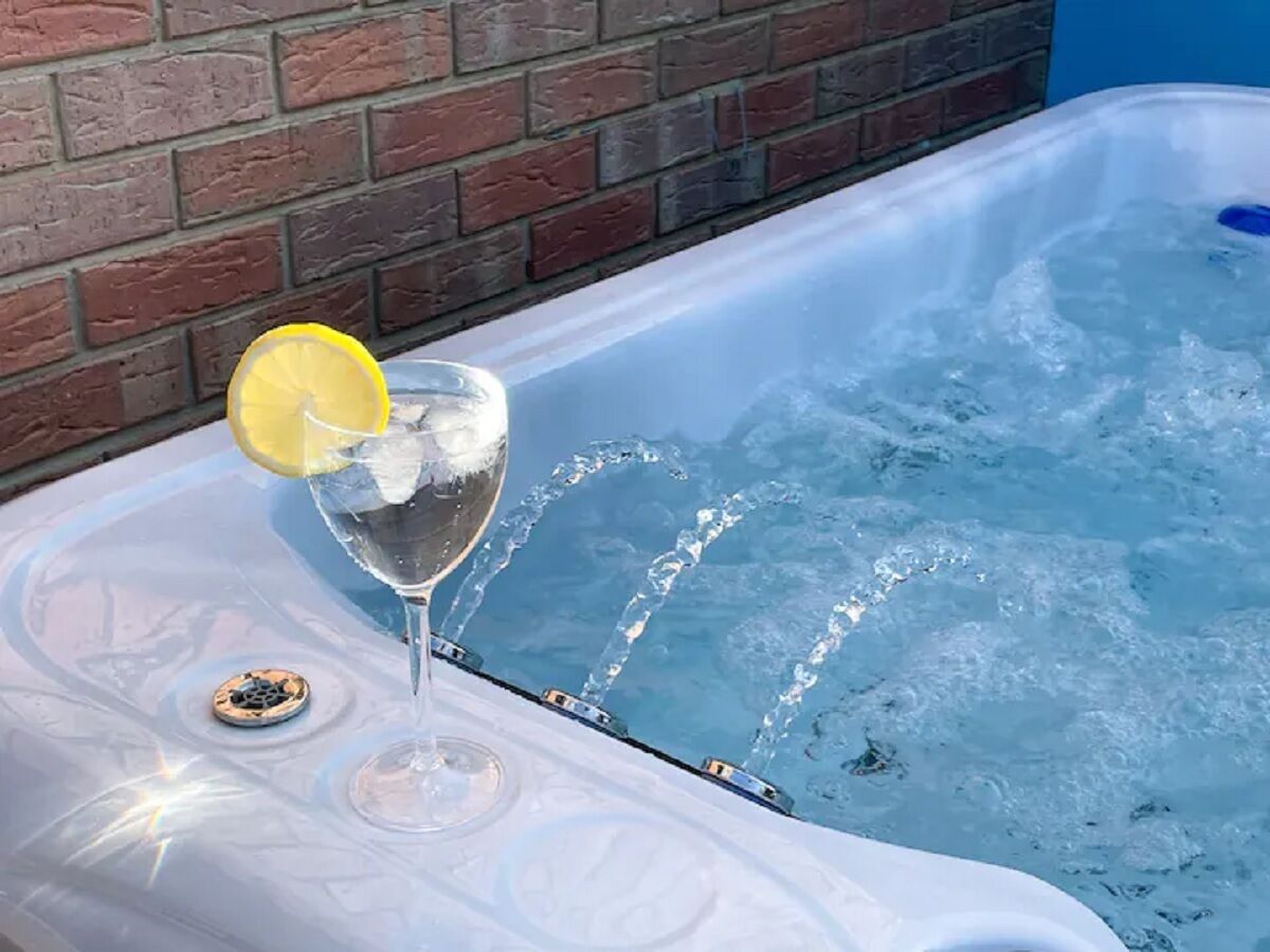 A hot tub with a glass of water and a lemon slice on the edge.