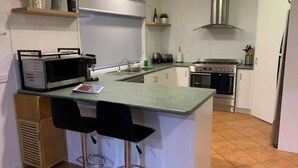 Une cuisine moderne dotée d’un îlot central, de tabourets de bar, d’un four à micro-ondes, d’une cuisinière et d’un évier.