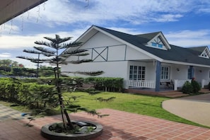 A modern house with a well-maintained garden, a circular driveway, and a clear sky. - English Resotel Hotel (Nakhon Si Thammarat)