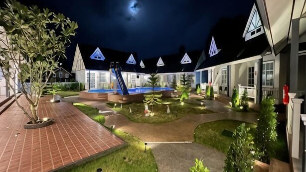 A courtyard with a pool, a slide, and a building with triangular roofs. - English Resotel Hotel (Nakhon Si Thammarat)