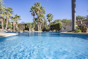 A clear blue swimming pool surrounded by palm trees and lounge chairs. - Modern Villa for 8 people with large pool and barbecue (Inca)