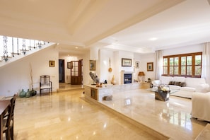 A spacious living area with a high ceiling, a fireplace, a staircase, and a dining area. - Modern Villa for 8 people with large pool and barbecue (Inca)