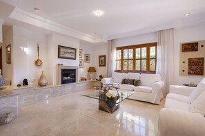 A spacious living room with a white sofa set, a glass coffee table, and a fireplace. - Modern Villa for 8 people with large pool and barbecue (Inca)