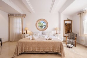 A spacious bedroom with a large bed, two bedside tables with lamps, a round window with a view, and a patterned chair. - Modern Villa for 8 people with large pool and barbecue (Inca)