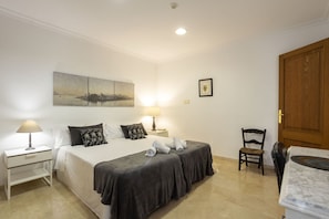 A hotel room with a bed, two bedside tables with lamps, a chair, a wooden door, and a cityscape painting on the wall. - Modern Villa for 8 people with large pool and barbecue (Inca)