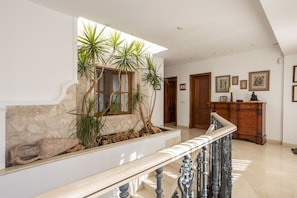 A spacious hallway with a stone wall, a wooden staircase, and a wooden cabinet with framed pictures. - Modern Villa for 8 people with large pool and barbecue (Inca)