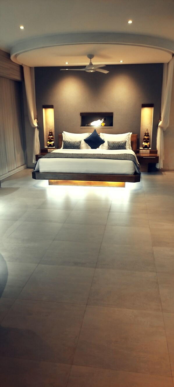 A modern hotel room with a large bed, a ceiling fan, and a nightstand with a lamp.