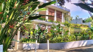 A modern building with a garden area featuring various plants and a sign that reads "HAYA DAING." - Rama Gaia Villa (Ubud)