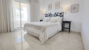 A bedroom with a bed, a nightstand, a lamp, and a view through a sliding door.
