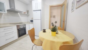 A compact kitchen with white cabinets, a stainless steel range, and a white refrigerator.