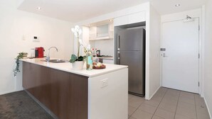 A modern kitchen with a central island, stainless steel appliances, and a minimalist design. - Executive Family Suite View Parking WiFi (Brisbane)
