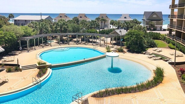 A resort pool with a circular shape, surrounded by lounge chairs and a covered area. - Saltwater Retreat, 2nd Floor, Spectacular Pool Area, Hot Tub, Free Beach Service (Miramar Beach)