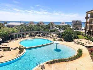 A resort pool with a circular shape, surrounded by lounge chairs and a covered area. - Saltwater Retreat, 2nd Floor, Spectacular Pool Area, Hot Tub, Free Beach Service (Miramar Beach)